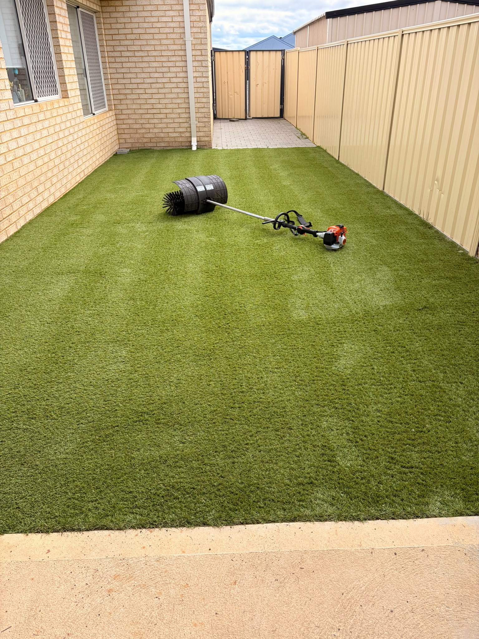 STIHL KB-KM bristle brush resting on a fully cleaned Perth backyard lawn, fibres evenly lifted end to end